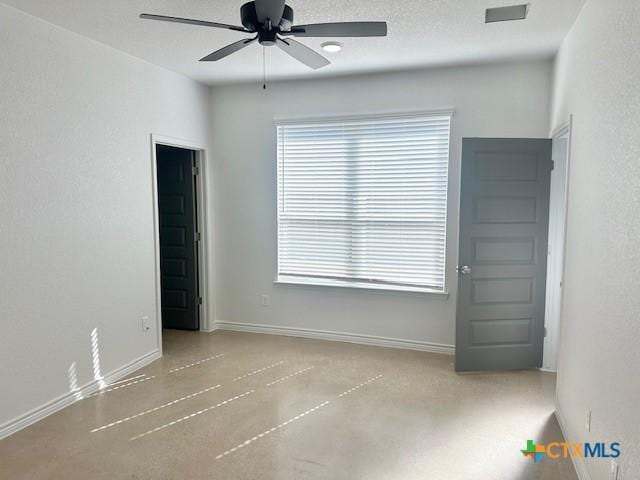 empty room featuring a ceiling fan, a textured ceiling, and baseboards