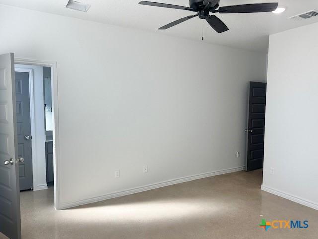 spare room with ceiling fan, finished concrete floors, visible vents, and baseboards