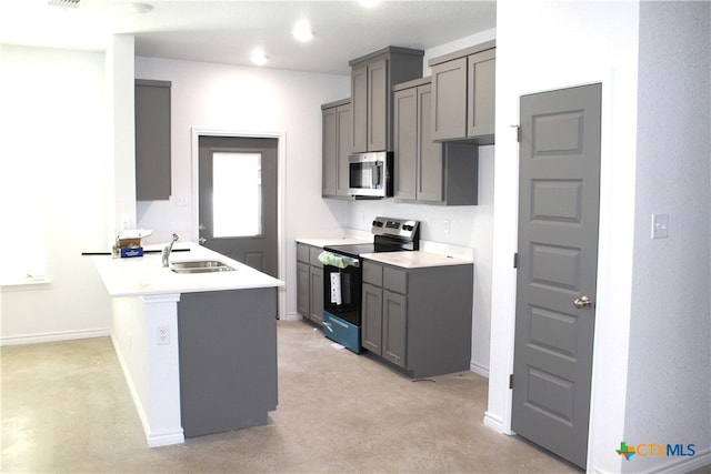 kitchen with gray cabinetry, appliances with stainless steel finishes, a kitchen bar, sink, and kitchen peninsula