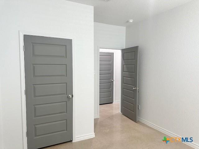 unfurnished bedroom featuring finished concrete flooring and baseboards