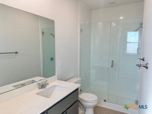 bathroom with a tile shower, vanity, and toilet