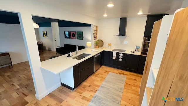 kitchen featuring a sink, wall chimney exhaust hood, dark cabinetry, light wood-style flooring, and black appliances