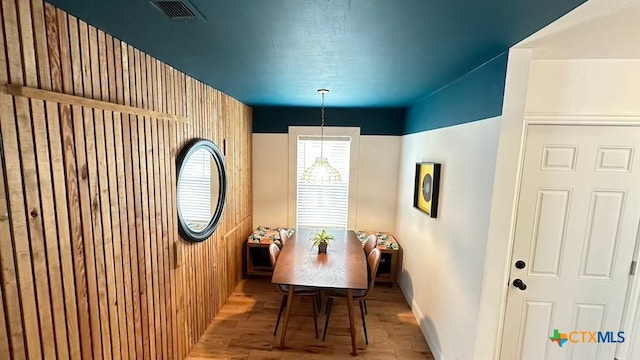 dining area featuring light hardwood / wood-style floors and wooden walls