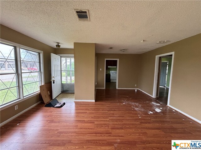 spare room featuring a textured ceiling and dark hardwood / wood-style flooring