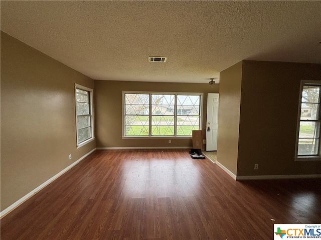 spare room with a textured ceiling and dark hardwood / wood-style flooring