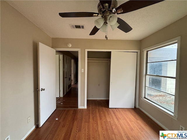 unfurnished bedroom featuring a closet, wood-type flooring, ceiling fan, and a textured ceiling