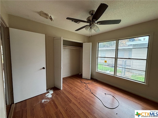 unfurnished bedroom featuring a textured ceiling, hardwood / wood-style floors, ceiling fan, and a closet