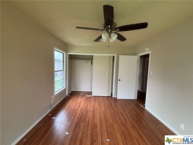 unfurnished bedroom featuring dark hardwood / wood-style flooring, a closet, a textured ceiling, and ceiling fan