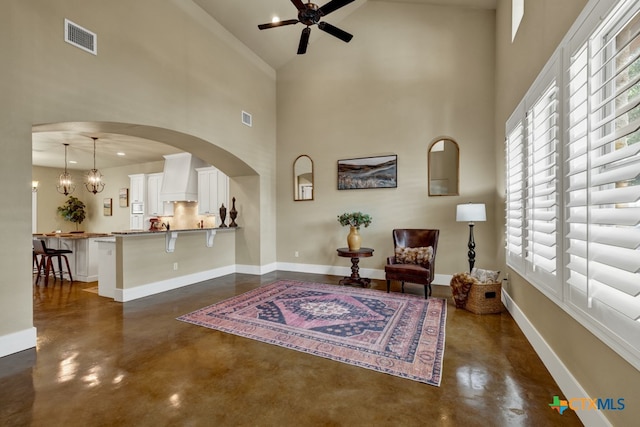 living area with a high ceiling, ceiling fan with notable chandelier, and plenty of natural light