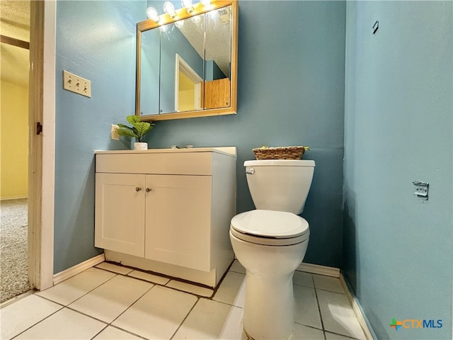 bathroom with toilet, vanity, and tile patterned flooring