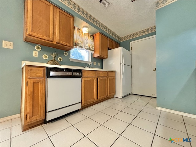 kitchen featuring white appliances, a textured ceiling, and light tile patterned floors