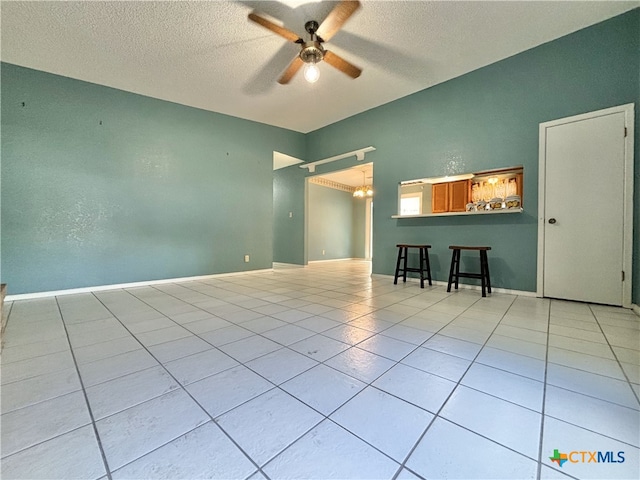 spare room with ceiling fan, a textured ceiling, and light tile patterned floors