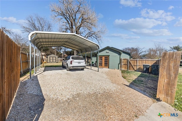 view of car parking featuring gravel driveway, a shed, fence, and a carport