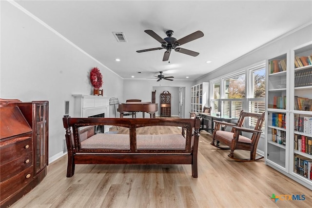 bedroom featuring crown molding, visible vents, a fireplace, and light wood finished floors