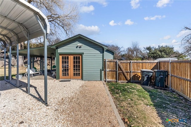 view of outbuilding with a detached carport, french doors, and fence