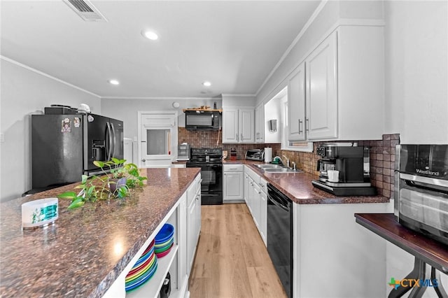 kitchen with decorative backsplash, white cabinetry, a sink, and black appliances