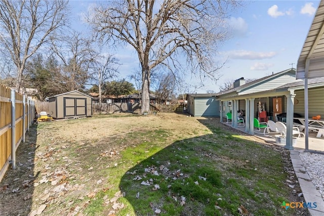 view of yard featuring a shed, a patio, a fenced backyard, and an outbuilding