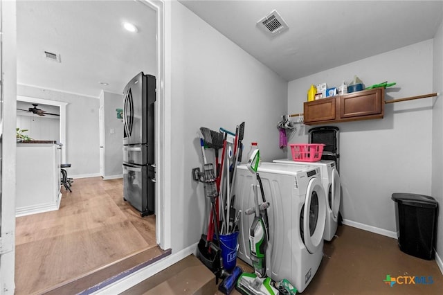 clothes washing area featuring washer and clothes dryer, cabinet space, visible vents, and baseboards