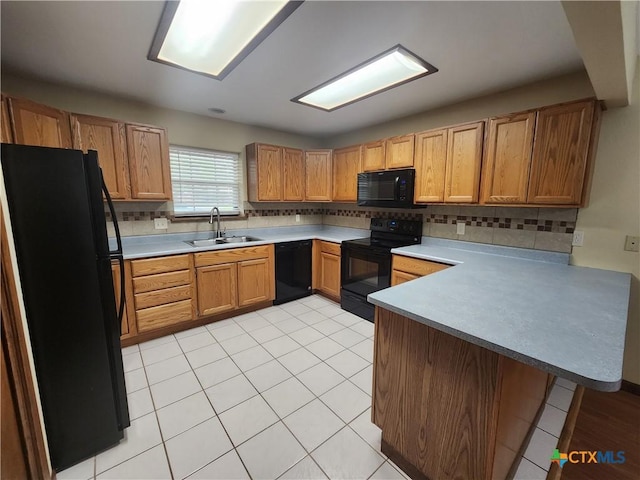 kitchen featuring backsplash, black appliances, sink, light tile patterned floors, and kitchen peninsula