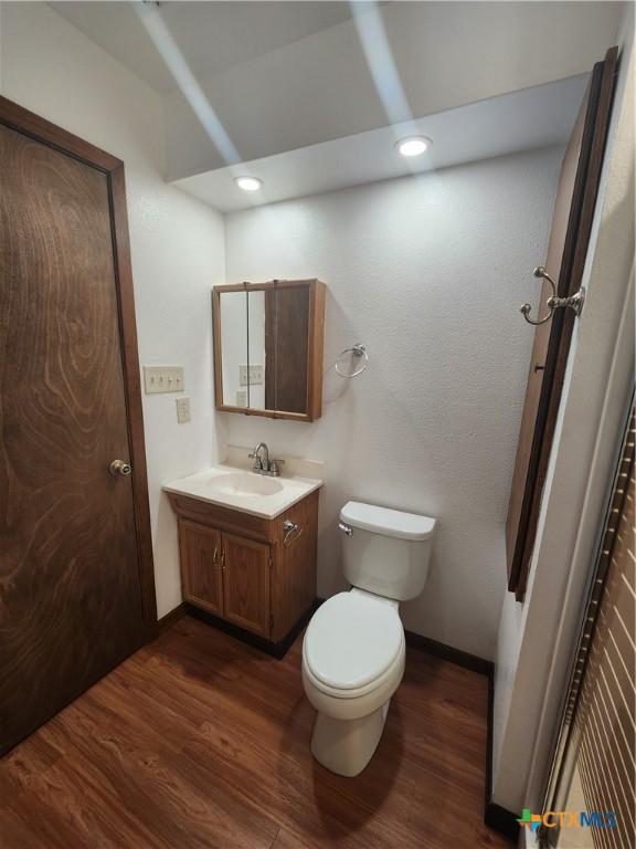 bathroom with toilet, vanity, and hardwood / wood-style flooring