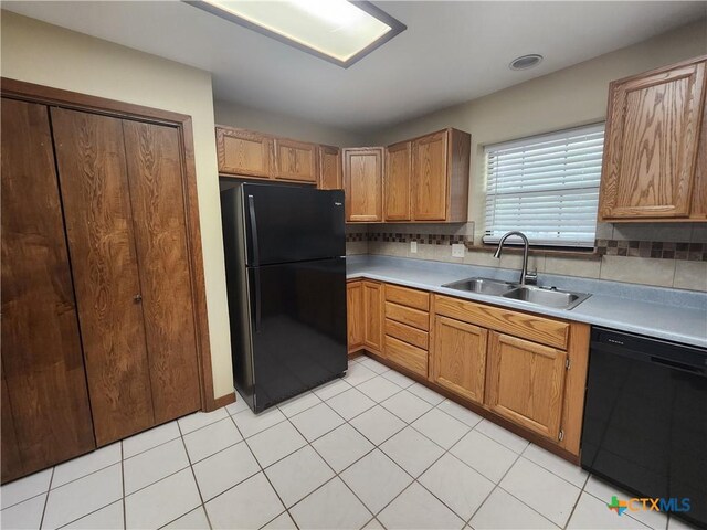 kitchen featuring light tile patterned flooring, sink, backsplash, and black appliances