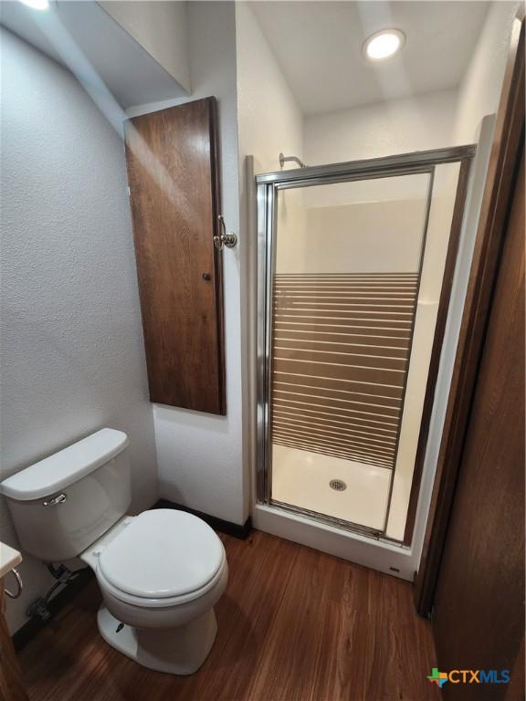 bathroom with hardwood / wood-style flooring, toilet, and an enclosed shower