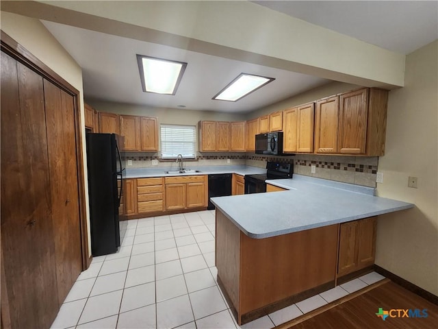 kitchen with kitchen peninsula, sink, tasteful backsplash, and black appliances