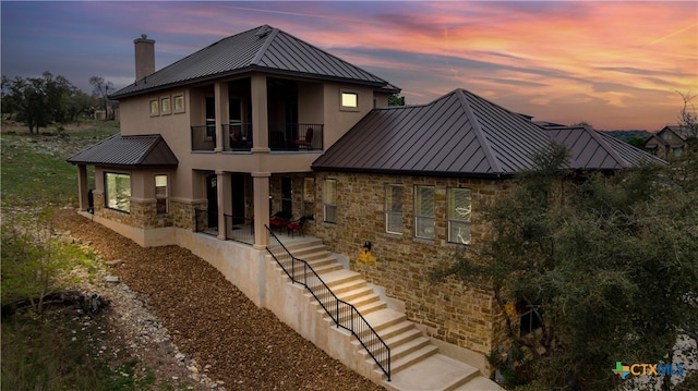 back house at dusk with a patio and a balcony