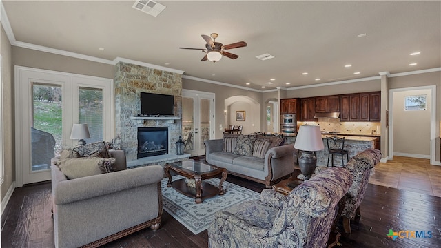 living room with a fireplace, dark hardwood / wood-style floors, ceiling fan, and ornamental molding