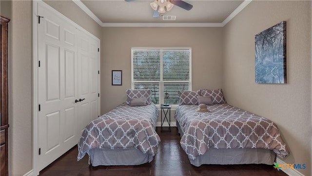 bedroom featuring dark wood-type flooring, a closet, ornamental molding, and ceiling fan