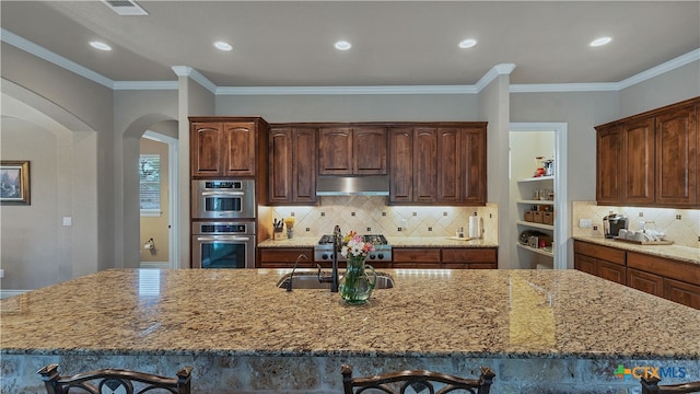 kitchen with crown molding, a spacious island, light stone counters, and tasteful backsplash