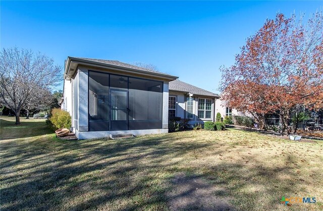 rear view of property featuring a sunroom and a yard