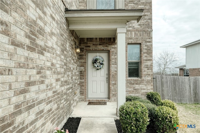 property entrance featuring brick siding and fence