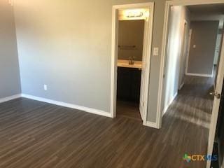 1818 Castroville Trl, Copperas Cove, TX 76522 - unfurnished bedroom with baseboards, dark wood-type flooring, and ensuite bath