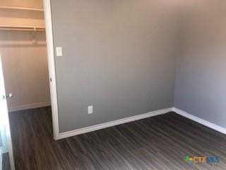 1818 Castroville Trl, Copperas Cove, TX 76522 - unfurnished bedroom featuring baseboards, dark wood-style floors, a walk in closet, and a closet