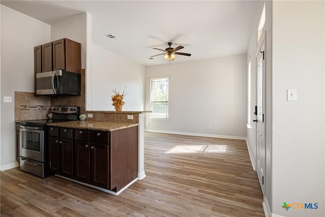180 Jim Bowie Dr, Paige, TX 78659 - kitchen featuring appliances with stainless steel finishes, a ceiling fan, light wood-style flooring, tasteful backsplash, and baseboards