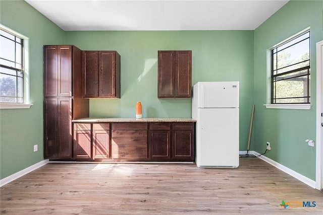 180 Jim Bowie Dr, Paige, TX 78659 - kitchen with freestanding refrigerator, light wood-style flooring, baseboards, and light countertops