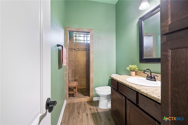 180 Jim Bowie Dr, Paige, TX 78659 - full bath featuring toilet, vanity, wood finished floors, tiled shower, and baseboards