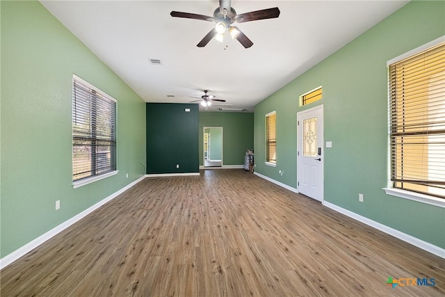 180 Jim Bowie Dr, Paige, TX 78659 - unfurnished living room featuring ceiling fan, plenty of natural light, wood finished floors, and baseboards