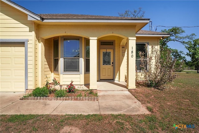 180 Jim Bowie Dr, Paige, TX 78659 - property entrance with roof with shingles, covered porch, and an attached garage