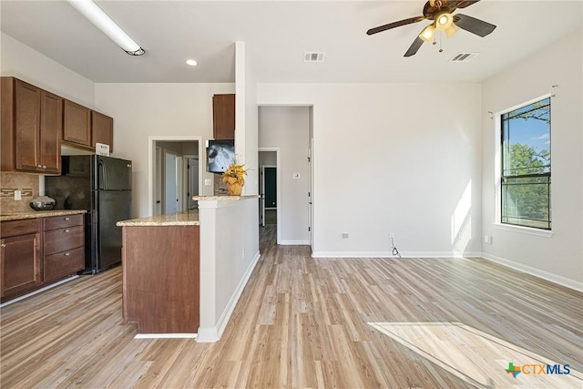 180 Jim Bowie Dr, Paige, TX 78659 - kitchen featuring light wood-style flooring, a ceiling fan, freestanding refrigerator, a peninsula, and backsplash