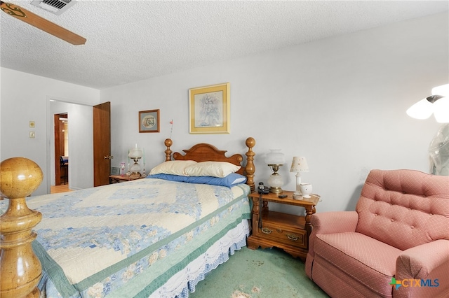 bedroom featuring a ceiling fan, visible vents, a textured ceiling, and carpet flooring