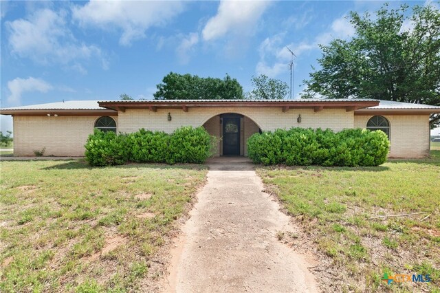 view of front of house with brick siding, metal roof, and a front yard