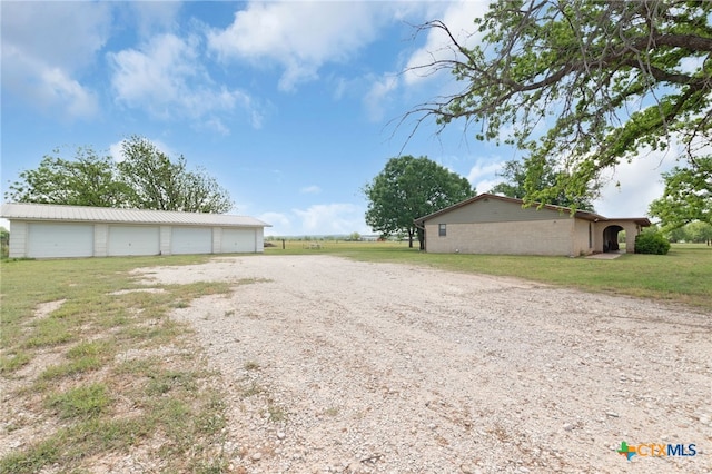 view of yard featuring driveway, an outbuilding, and a detached garage