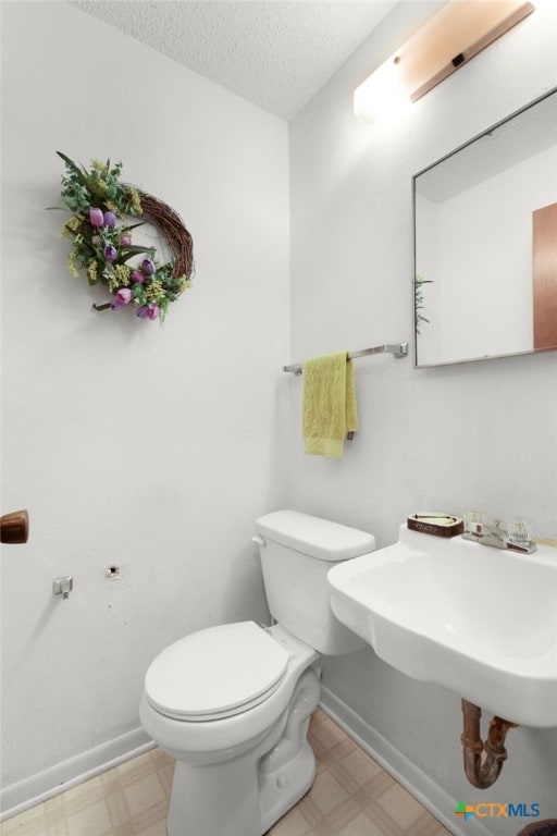 bathroom featuring toilet, tile patterned floors, a textured ceiling, and baseboards