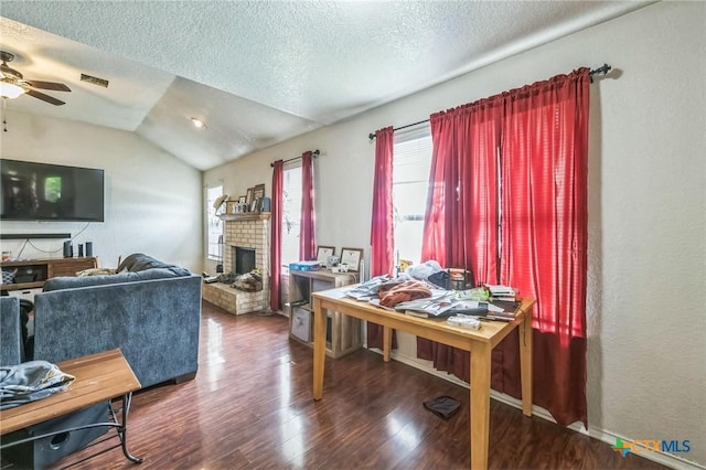 interior space with a ceiling fan, a brick fireplace, visible vents, lofted ceiling, and wood finished floors