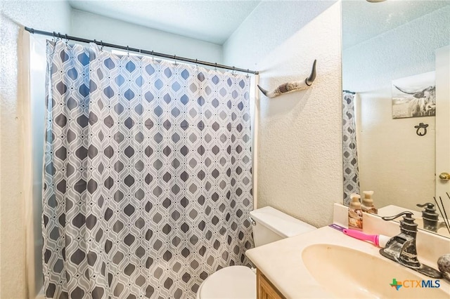 bathroom with toilet, a shower with curtain, vanity, and a textured wall