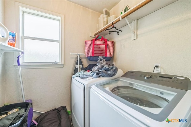 clothes washing area with independent washer and dryer, laundry area, and a textured wall