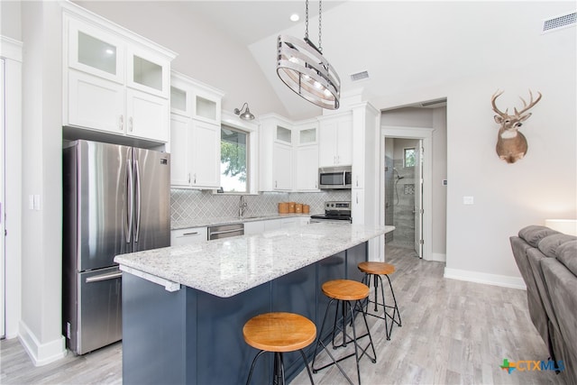 kitchen with light hardwood / wood-style flooring, a center island, white cabinets, and stainless steel appliances