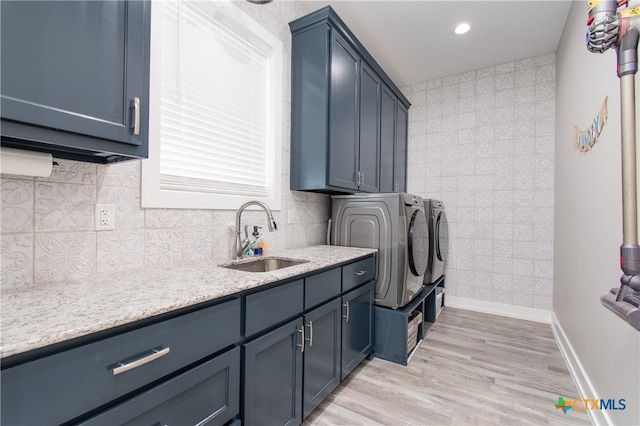 laundry room featuring cabinets, washer and dryer, sink, and light wood-type flooring